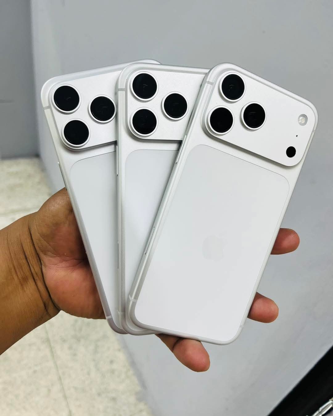 Tres iPhone 16 Pro Max color plata en mano